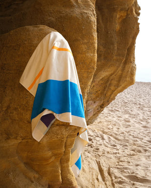 Colorful towel draped over a rock on a sandy beach